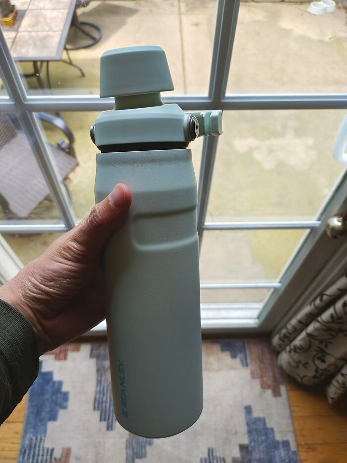 Hand holding a light blue water bottle by a window, one of the top back to school finds for your cart before chaos.