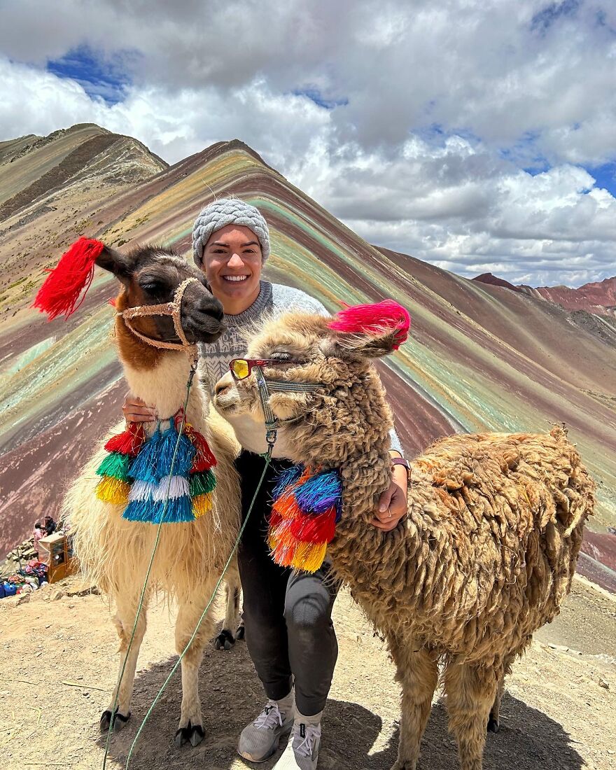 Traveler smiling with llamas at colorful mountain landscape representing one way flight to Australia journey and transformation.