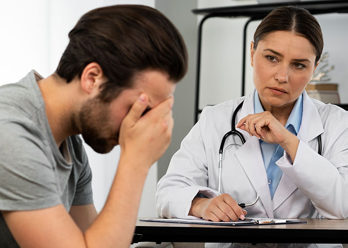 Man feeling sick and distressed while talking to a female doctor in a clinical setting about food his dad has touched.