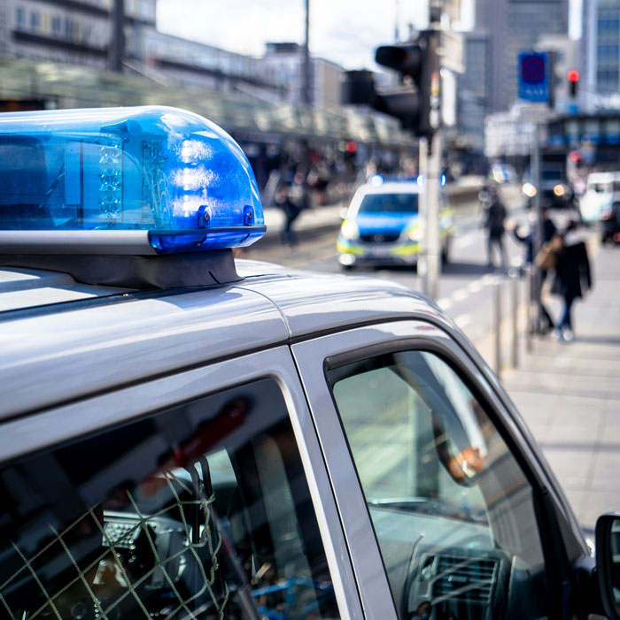 Police vehicle with blue lights parked on city street, related to roommates refusing to give back AC and illegal activities case.