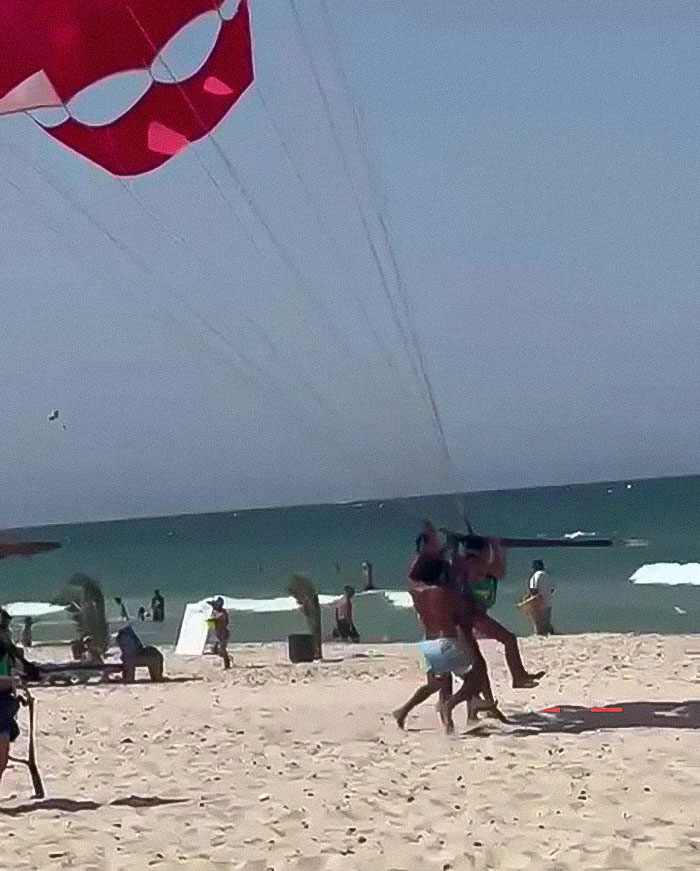 Woman preparing for parasailing on a sunny beach with others nearby, highlighting mid-air assault concerns during parasailing activity. - 10