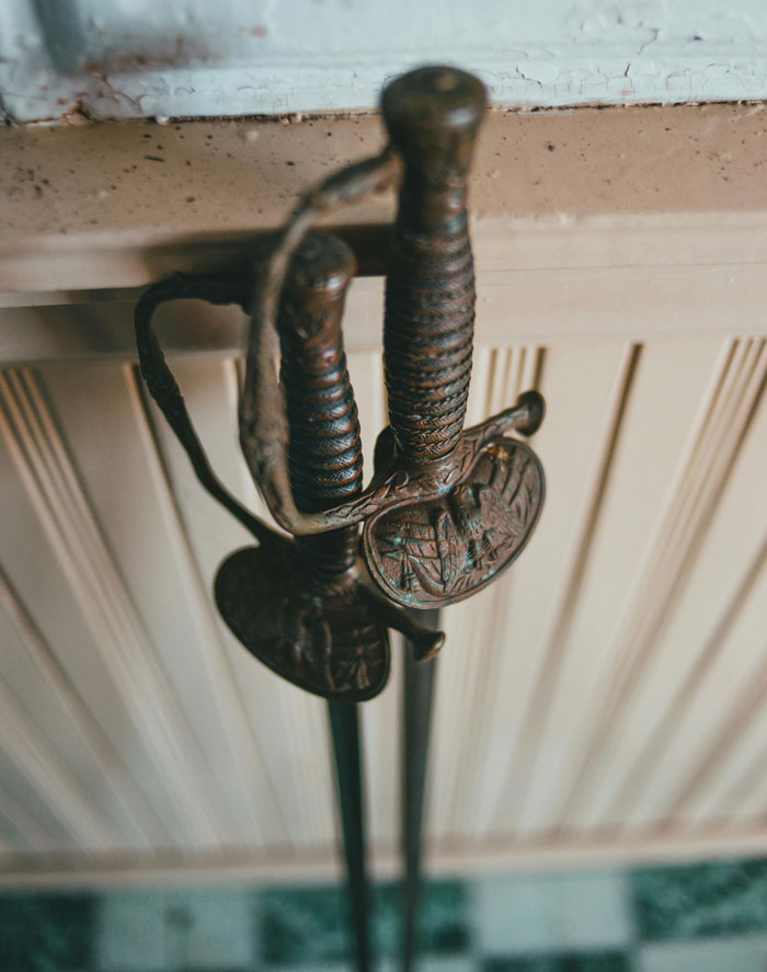 Antique decorative swords with detailed handles leaning against a wall, illustrating unhinged wedding spends. - 26