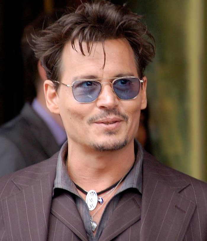 Man wearing blue sunglasses and layered necklaces, showcasing an insane family flex style with confidence.