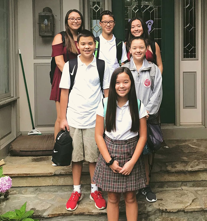 Kate and Jon Gosselin&rsquo;s children standing on porch steps, smiling and wearing backpacks for school.