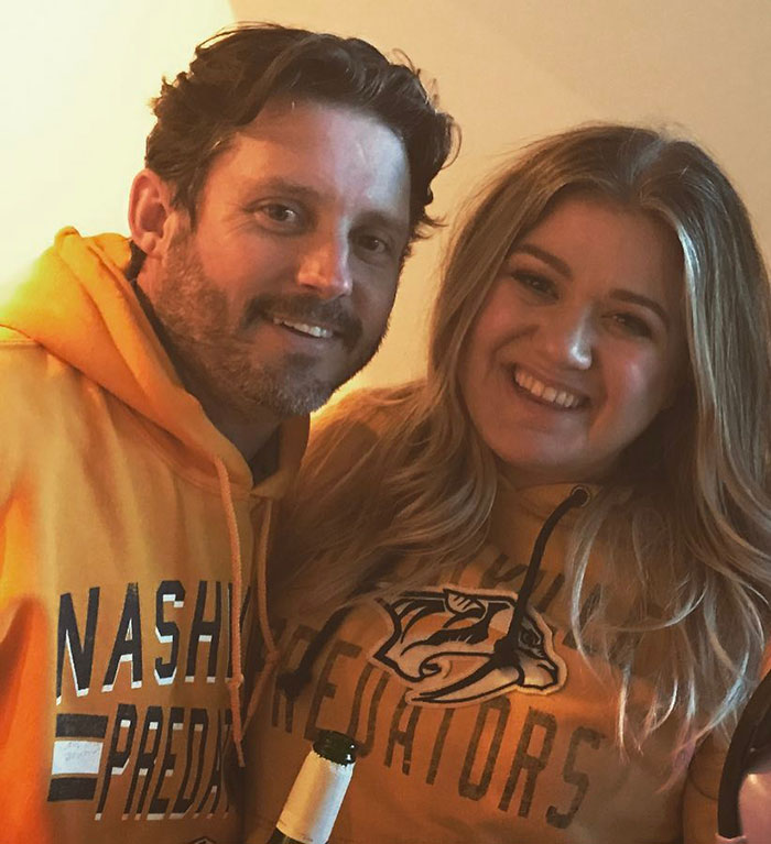 Brandon Blackstock and Kelly Clarkson's ex-assistant smiling together wearing Nashville Predators hoodies indoors.
