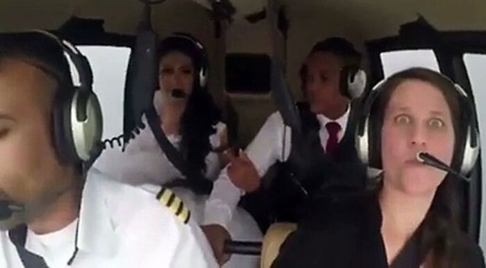Four people inside a helicopter cockpit, one with wide eyes, unsettling moment captured by Morbid Knowledge group members.