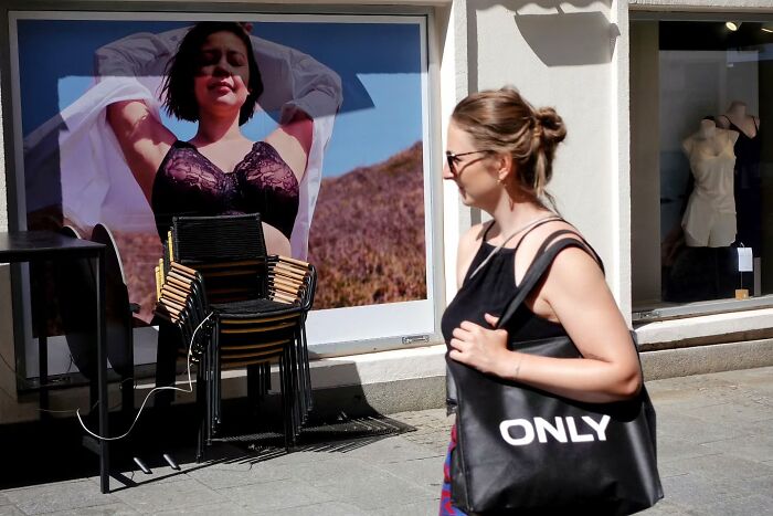 Woman walking past a street photo display capturing candid street moments by photographer Gerhard Wagner on a sunny day.