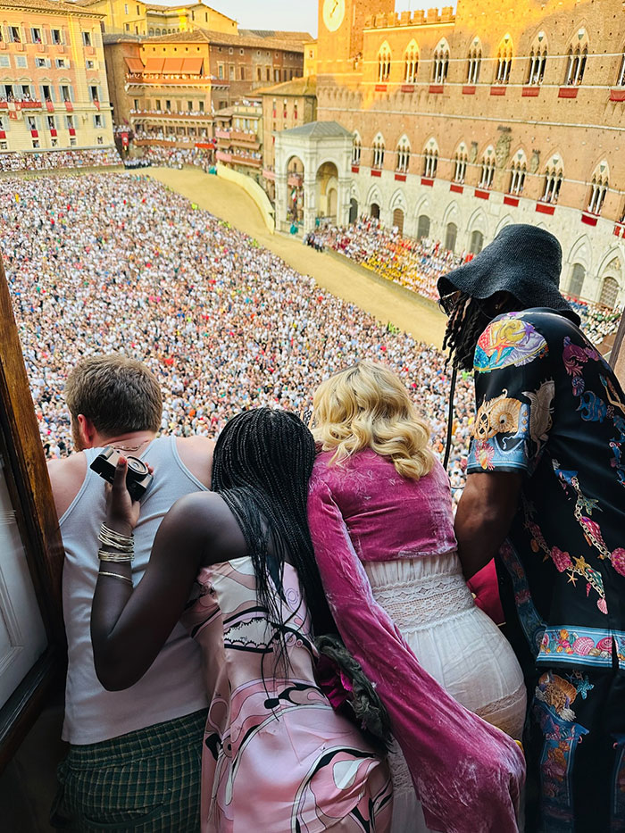 Group of people overlooking large outdoor crowd at a birthday party, featuring Madonna's daughter Lourdes in a pink outfit.