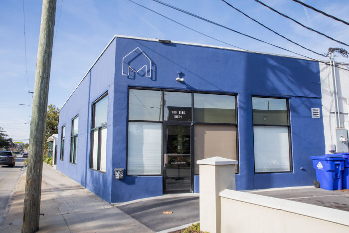 Blue commercial building on a sunny day with a sign, related to Uber driver incident involving service dog and CEO.