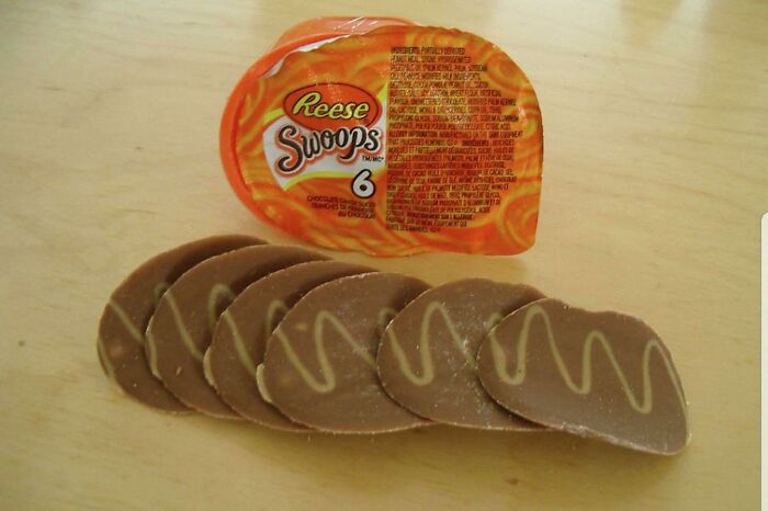 Reese Swoops chocolate candy on a wooden surface, evoking 90s kids nostalgia with its nostalgic design and flavor.