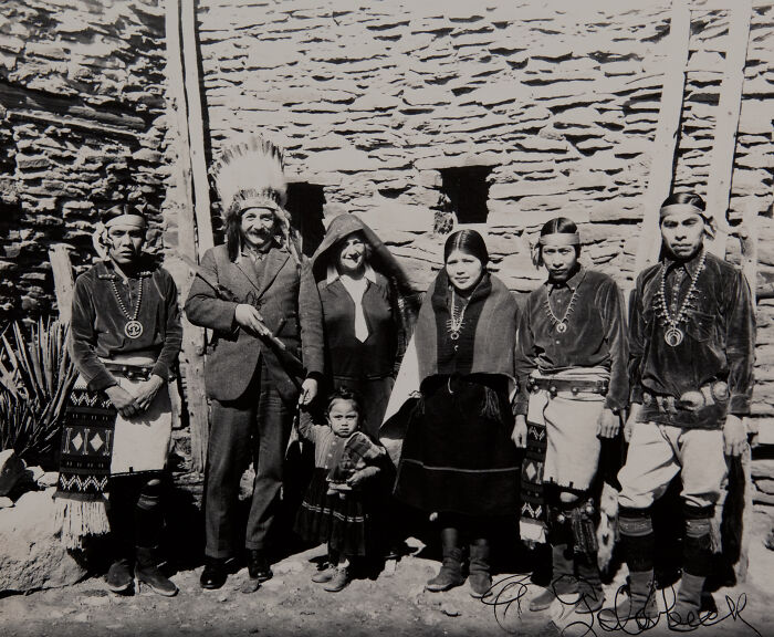 Vintage historical photo of a Native American family and visitors in traditional attire, showcasing rare historical moments.