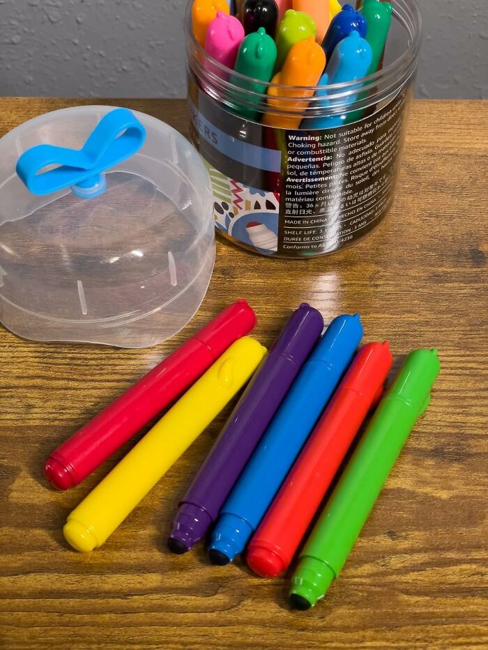Colorful markers arranged on a wooden surface next to a container, perfect back to school finds for students.