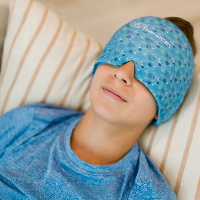 Person lying down wearing a blue ice pack eye mask, one of the brilliant Amazon finds for comfort and relief.