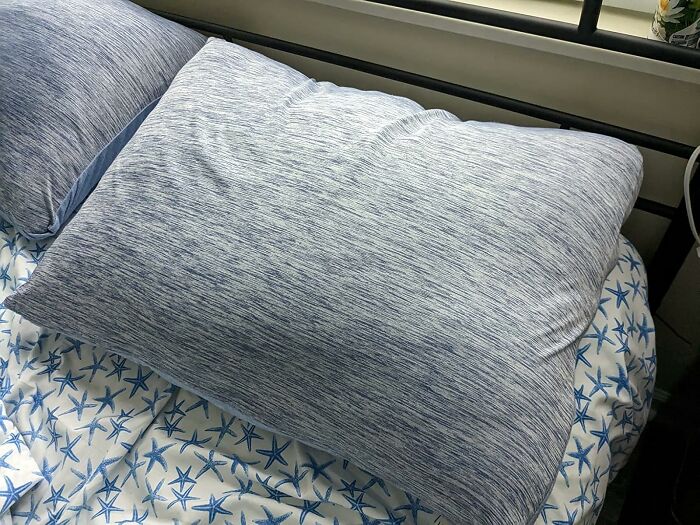 Cooling pillow on bed with starfish-patterned sheets representing heatwave hacks for summer comfort.