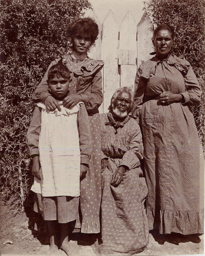 Indigenous Australians family from the 1900s posing outdoors in traditional clothing, capturing rare historical moments.