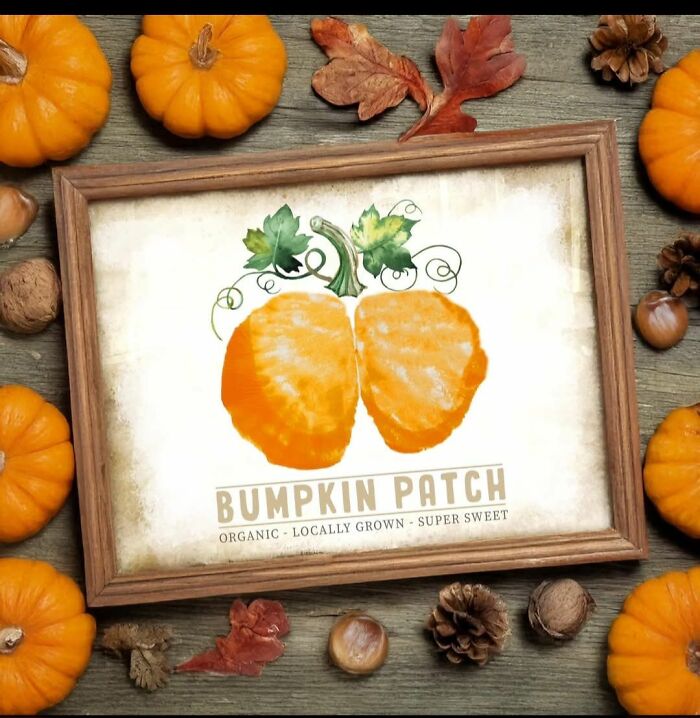 Framed craft project of a pumpkin painting surrounded by small pumpkins, pinecones, nuts, and autumn leaves on wood.