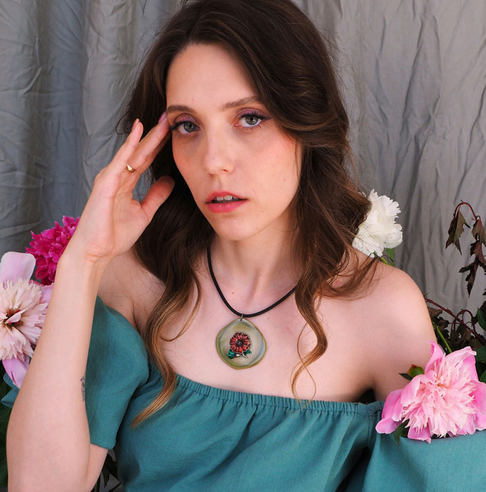 Woman in green off-shoulder top looking upset among flowers, expressing frustration with coworker taking her food.
