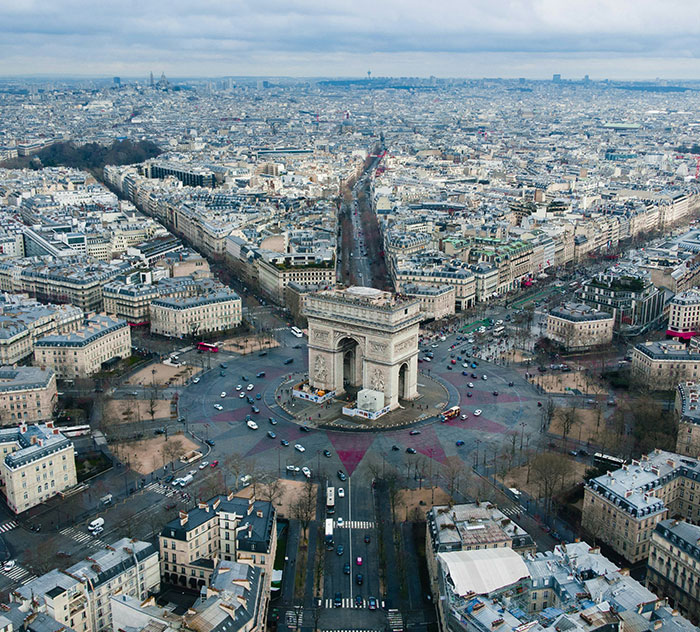 Aerial view of the Arc de Triomphe and surrounding Paris streets near the Tomb of Unknown Soldier monument.