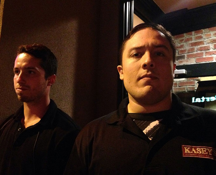 Two bar staff members standing alert at a venue, ready to protect women from uncomfortable situations with men.