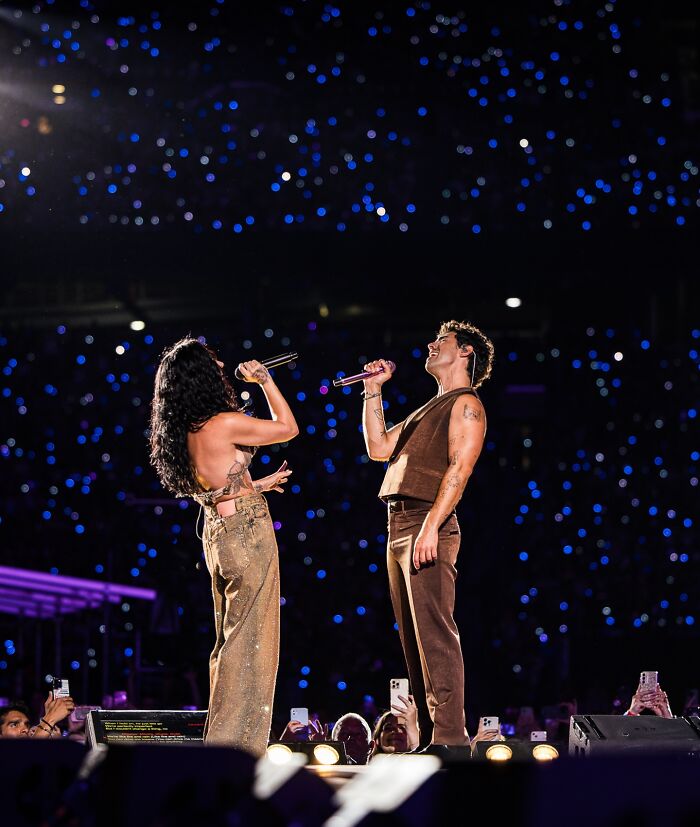 Nick Jonas performing on stage with a female singer during a concert, illustrating his revelation about never sitting in bed with his wife. Nick Jonas performing on stage with a female singer during a concert, illustrating his revelation about never sitting in bed with his wife.