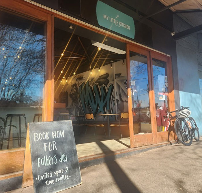 Caf&eacute; exterior with a sign promoting Father's Day bookings, highlighting caf&eacute; owner addressing entitled customers and teen worker emotions.