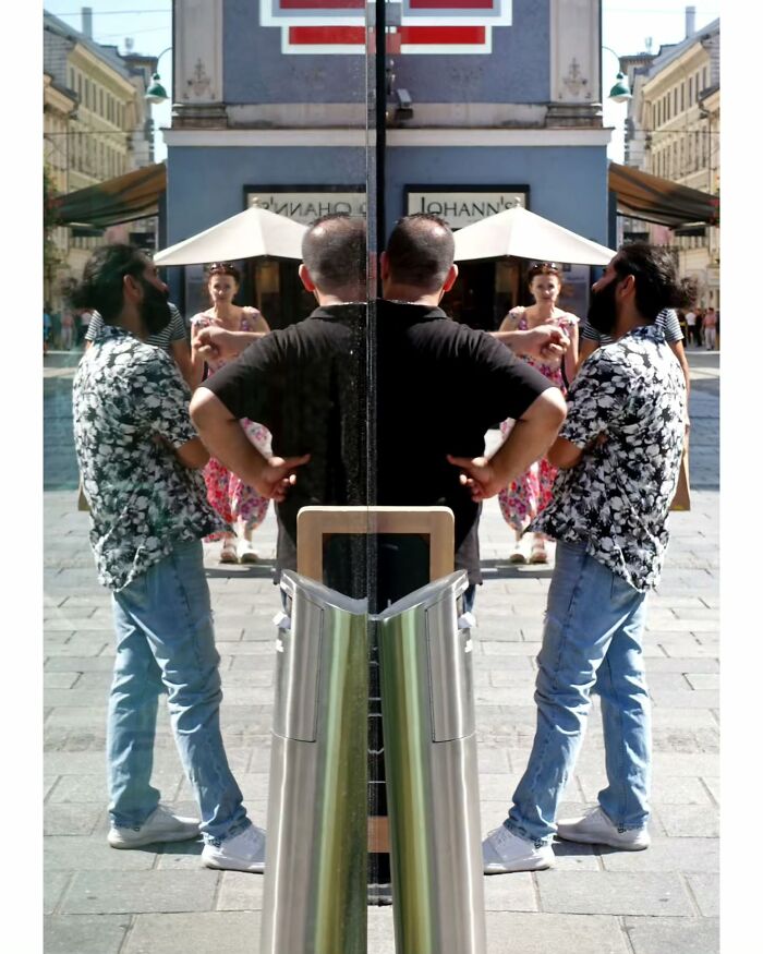 Two men captured in an unseen, unposed moment on the streets, reflected in a glass panel during a sunny day.