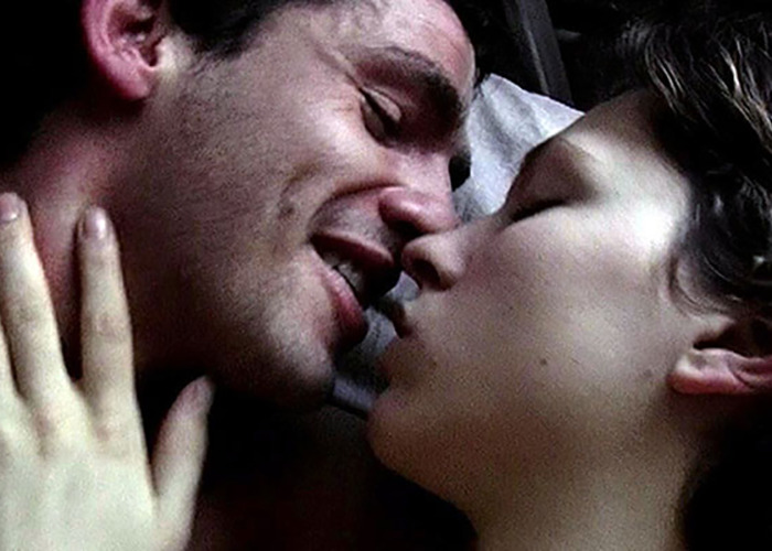 Close-up of movie stars intimately embracing while filming love-making scenes for a romantic film.