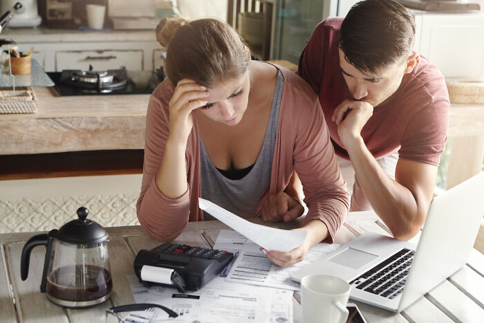 Couple reviewing bills at kitchen table, focusing on low effort high reward ways to manage finances effectively.