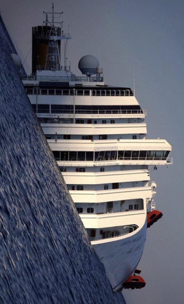 Cruise ship tilted at an extreme angle in the water, creating an unsettling and eerie scene from morbid knowledge.