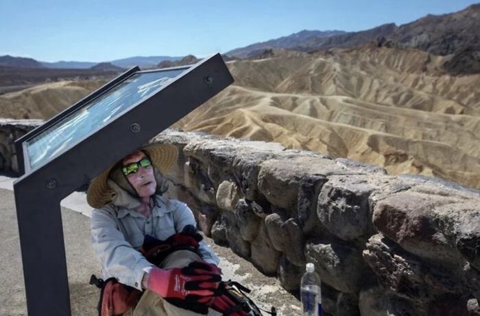 Person resting near a stone wall with desert hills in the background, an unsettling image from Morbid Knowledge group.