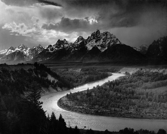 Black and white landscape of dramatic mountains and winding river, capturing a triumph and tragedy of the 20th century moment.