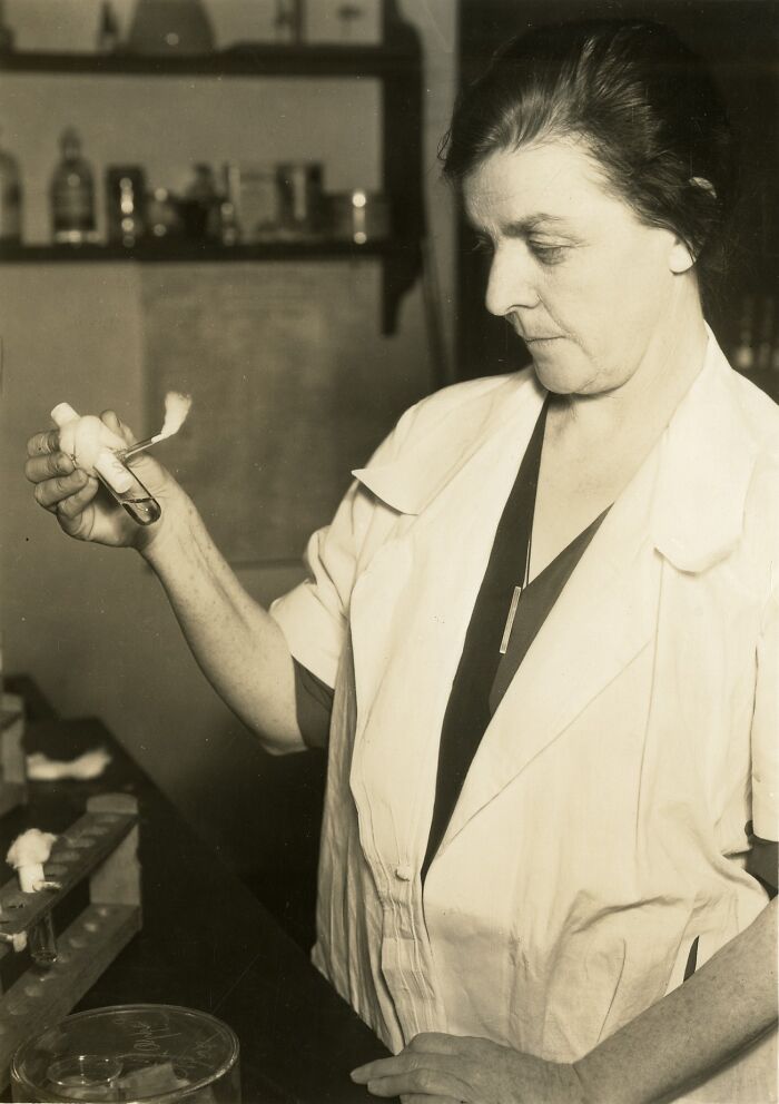 Woman scientist in a lab coat conducting a test with a test tube, representing remarkable women scientists in Smithsonian portraits.