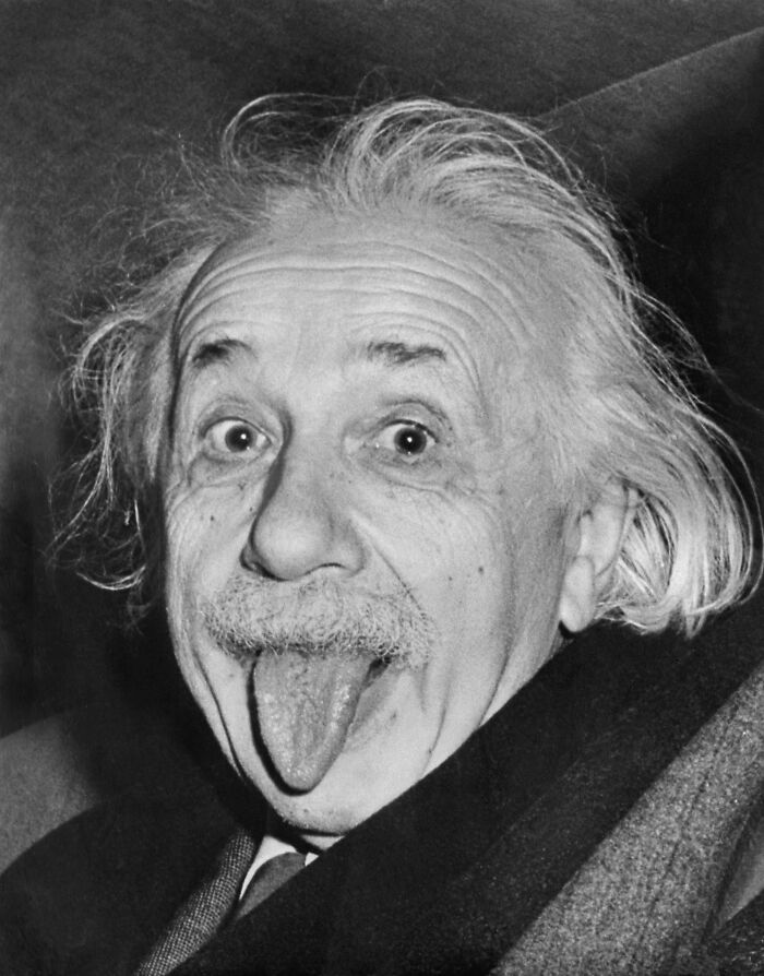 Black and white photo of Albert Einstein playfully sticking out his tongue, a triumph and tragedy 20th century image.
