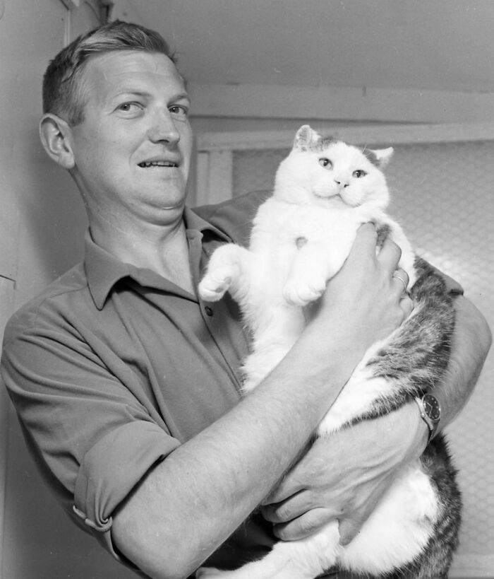 Man holding a large vintage cat in a black and white photo showcasing classic pet moments before the internet era
