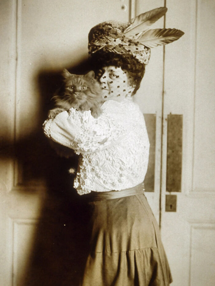Vintage black and white photo of a woman in period clothing holding a fluffy cat, classic vintage cat photo style