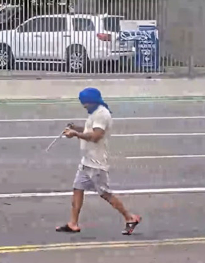 Man walking on street wearing blue head covering and casual clothes, related to woman chased by man with machete incident.