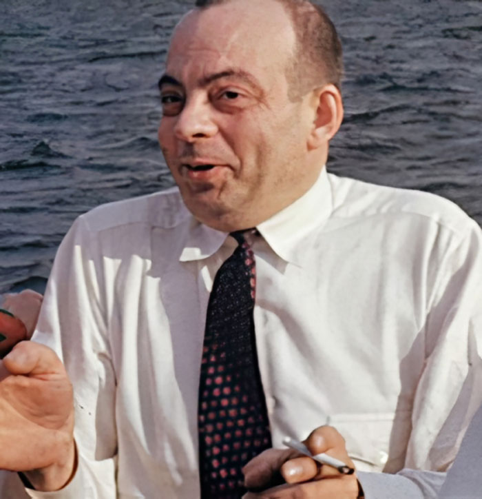 Man in a white shirt and patterned tie holding a cigarette near water, related to celebrities and unsolved disappearances.