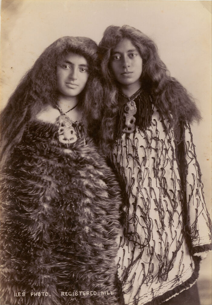 Two Māori women in traditional clothing and jewelry, captured in powerful portraits of Māori life a century ago.