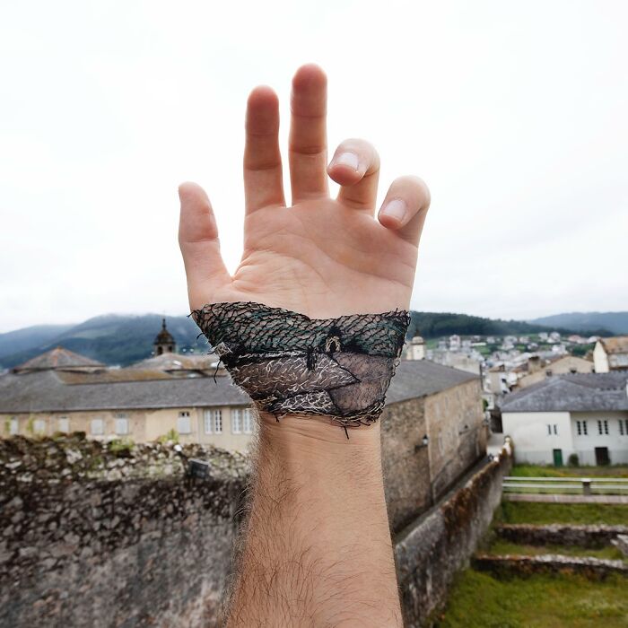 Hand with detailed landscape stitched onto skin, showcasing creative artist's unique landscape embroidery art on wrist.