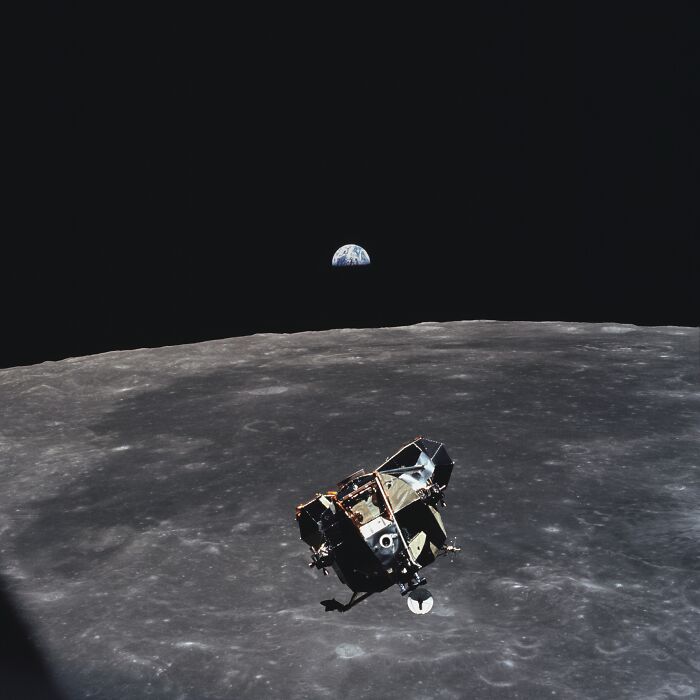 Lunar module flying above the moon’s surface with Earth rising in the background, iconic moments in history photo.