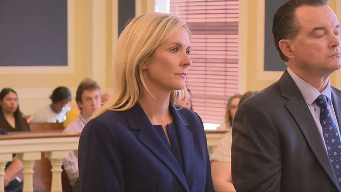 Prosecutor in courtroom wearing navy blazer during hearing related to viral video threatening cops arresting her.