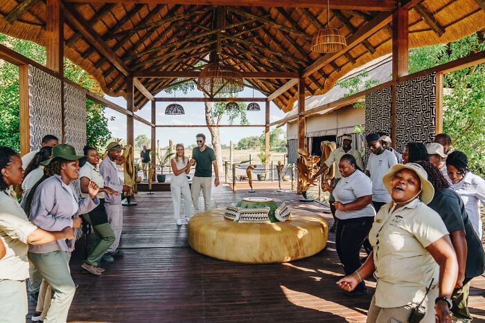 Group of safari guides and tourists enjoying a lively welcome at a lodge in the Okavango Delta, Botswana.