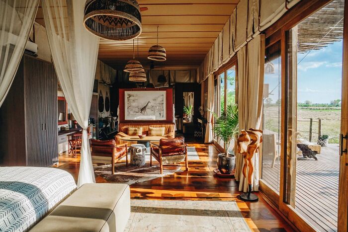 Luxurious Okavango Delta lodge interior with natural light, wooden floors, and views of the outdoor deck and surrounding landscape.