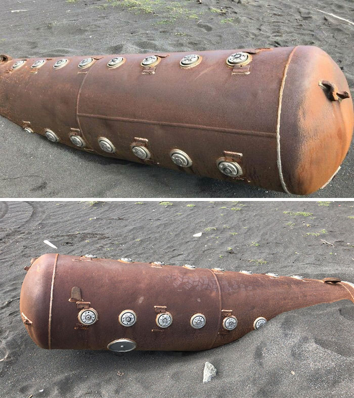 Rusty metal object with circular attachments found on a sandy beach among interesting and bizarre beach discoveries.
