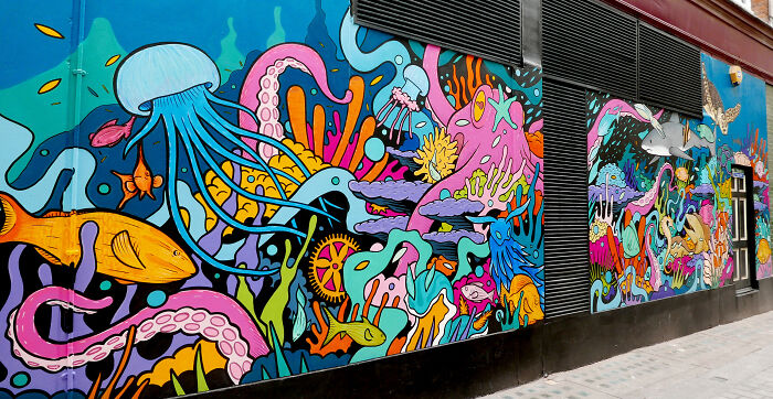 Vibrant street art mural featuring colorful underwater creatures and abstract shapes on an urban building wall.
