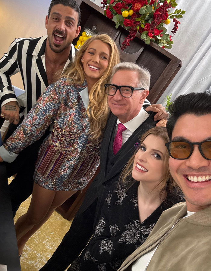 Blake Lively with cast and director smiling on set of new rom-com, capturing a joyful group moment indoors.