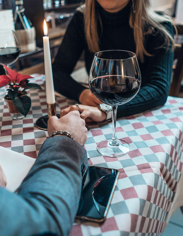 Couple holding hands on a romantic dinner date with wine and candlelight, adult star Bonnie Blue new romance ambiance.