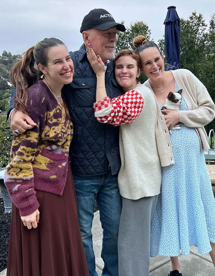 Bruce Willis with family outdoors, smiling and embracing, highlighting update from his wife amid dementia battle and separate living.