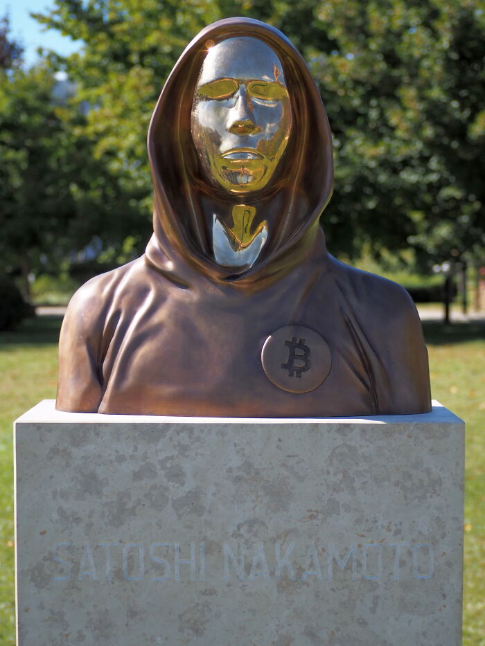 Bronze statue of a hooded figure with a Bitcoin symbol, representing one of the world's greatest unsolved mysteries.