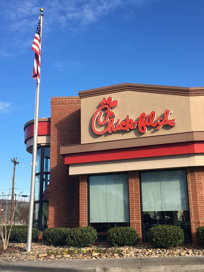 Chick-fil-A restaurant exterior with clear blue sky, focusing on building and flagpole, representing glitches in the matrix.